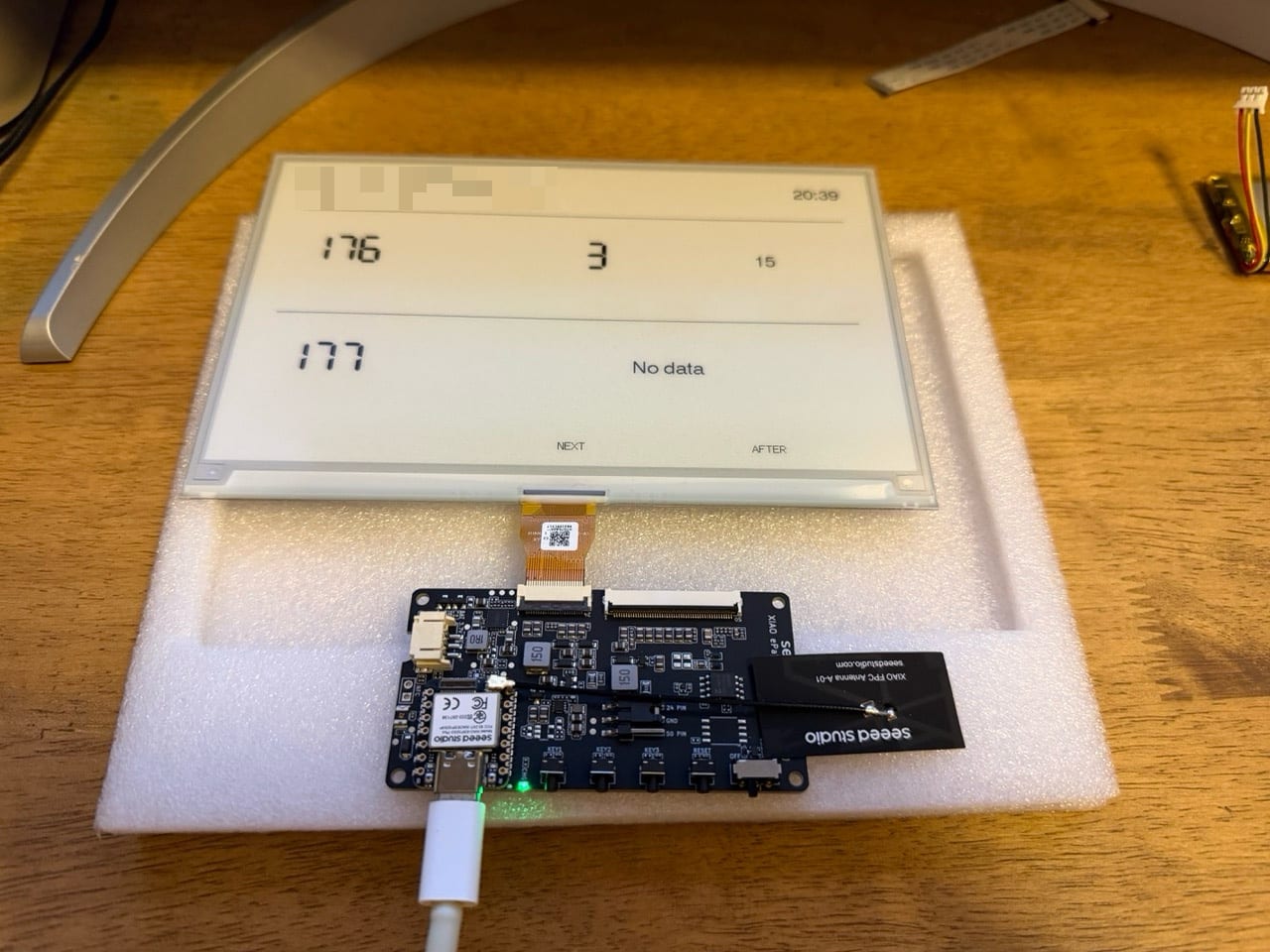 The bare driver board on a piece of packing foam, connected to the panel by a ribbon cable, with a USB-C cable plugged in and the screen showing a very basic bus list